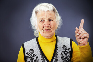 Closeup portrait senior mature woman pointing with index finger hand upwards, one sign, got idea trying to remember  