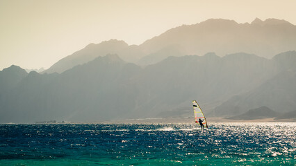 one surfer rides in the Red Sea against the backdrop of a rocky coast in Egypt in the evening