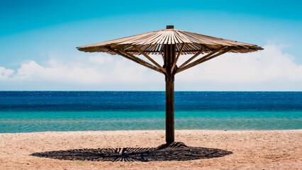wooden beach umbrella on the shore without people of the Red Sea in Egypt