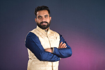 Portrait of a happy young man posing with arms crossed or hands folded on a dark background