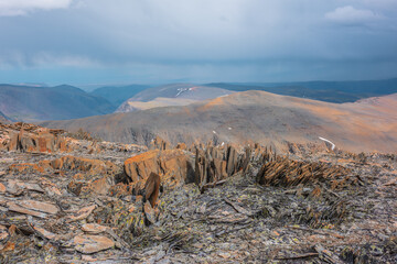 Sharp stones on high sunlit stony mountain pass with view to big rocky hills and large mountain...