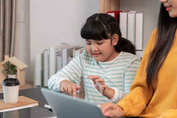 Smiling mother and daughter using laptop together at home