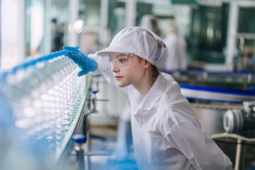 Women worker focus working care quality control in Drinking water factory. Production line...