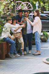 Stylish young people, men and women, friends, colleagues meeting at outdoor bar after work, enjoying beer and conversation. Party, weekends and celebration. Concept of relaxation, party, beer