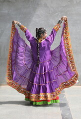 Naklejka premium woman is wearing ruffled shrug of purple bandhani print. full flare banjara shrug on chaniya choli for garba in navratri. Traditional gujarati outfit with long braid. Unique navratri look and outfit. 