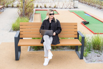 A businesswoman using a laptop on a golf course