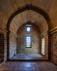 Inside a historic stone chamber, the sunlight filters through an ornate window, highlighting the...