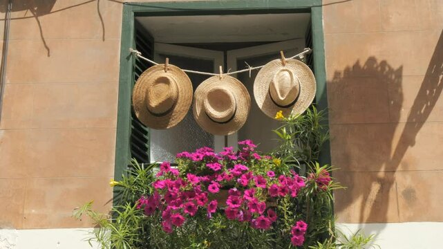 Spanish vibe. Decorated window with straw hats and flowers on a summer day