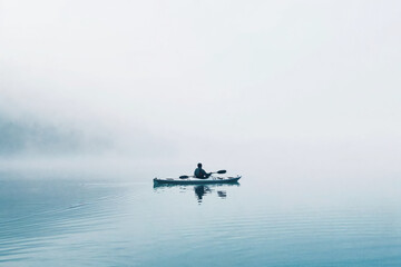 Fototapeta premium Anonymous paddler in a serene, foggy waterscape. Generative AI image