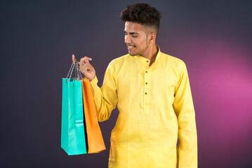 Indian traditional Young handsome man holding and posing with shopping bags on a dark background