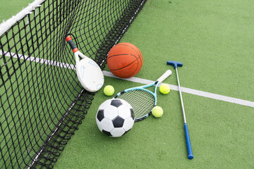 A variety of sports equipment including an american football, a soccer ball, a tennis racket, a tennis ball, and a basketball