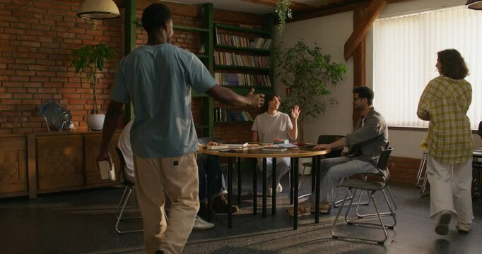 Young people of different nationalities gather at a table to study the Bible together. Stylish room, daylight