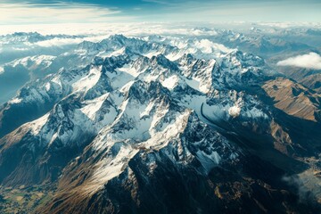A beautiful aerial landscape of a snow-covered mountain range under a partly cloudy sky, capturing the pristine and rugged beauty of the natural terrain.