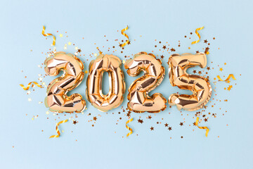 2025 New Year holidays concept. Golden inflatable balloons, ribbons and glittering stars confetti...