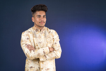 Portrait of a happy young man posing with arms crossed or hands folded on a dark background