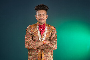 Portrait of a happy young man posing with arms crossed or hands folded on a dark background