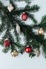on a spruce branch there are red and gold Christmas tree decorations on a light background
