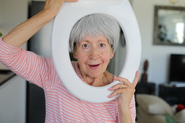 Senior comedian holding toilet part around her face 
