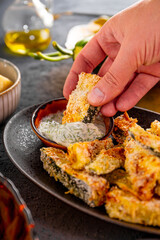 Healthy zucchini fries with yogurt and herbs sauce in the hand