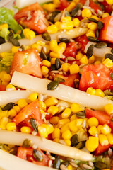 Close-up of a plate of tomato salad, asparagus, corn,...
