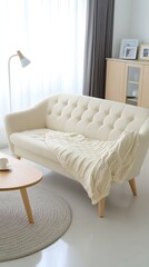 This stylish living room showcases a white sofa adorned with light pink pillows, draped in a beige blanket, under a large pendant lamp with boho elements creating a cheerful atmosphere