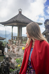 Tourist woman at a Hindu temple in Bali. Blonde woman. Model in classic Balinese outfit