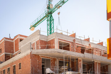 Vivid capture of construction site showcasing building in progress with brickwork and crane lifting...