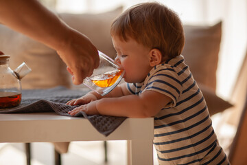 Small child under one year old plays in the room against the backdrop of wigwam in beige shades. The infant baby is happy and dressed  bodysuit. The cozy home environment © Вероника Зеленина