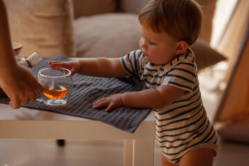 Small child under one year old plays in the room against the backdrop of wigwam in beige shades. The infant baby is happy and dressed  bodysuit. The cozy home environment © Вероника Зеленина