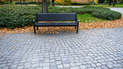 A serene park setting showcases stunning autumn colors as trees shed their leaves. An empty bench offers a perfect spot for relaxation along a charming cobblestone path