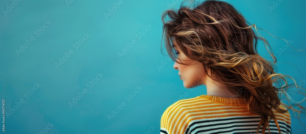 Fototapete a woman with wavy hair in a fashionable striped sweater is set against a blue background with blank 
