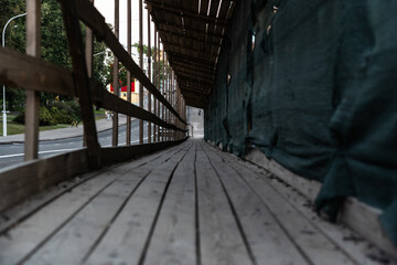 A wooden, temporary pedestrian crossing past the construction site. Evening City