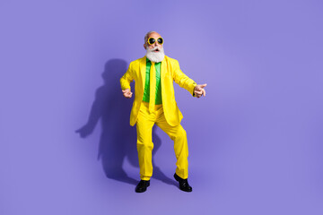 Photo of cool positive funny senior man wearing stylish yellow costume have fun empty space isolated on purple color background