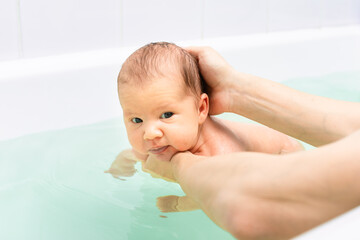 Mother bathing newborn baby in gentle water