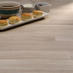 Afternoon Tea Scene with Scones, Jam, Clotted Cream, and a Cup of Coffee on a Light Wooden Floor