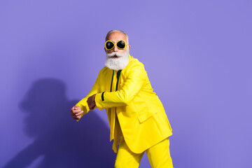 Portrait of funny extravagant aged man dance good mood yellow suit isolated on purple color background