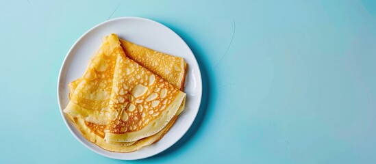 Crepes thin Russian pancakes on a white plate set against a pastel blue background Top view. Copy...