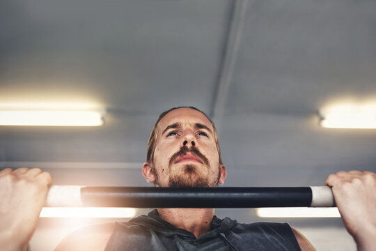 Athlete, strong man and pull ups for exercise, fitness and wellness with health, muscle and training. Serious, male person and bodybuilding for sport with bar, upper body workout for endurance in gym