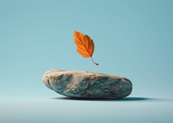 Naklejka premium A single rock with a floating autumn leaf above it, set against a soft blue background The scene captures a serene and minimalist aesthetic