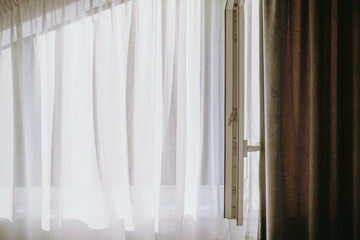 Lightly flowing sheer curtains near an open window in a softly lit room during the day