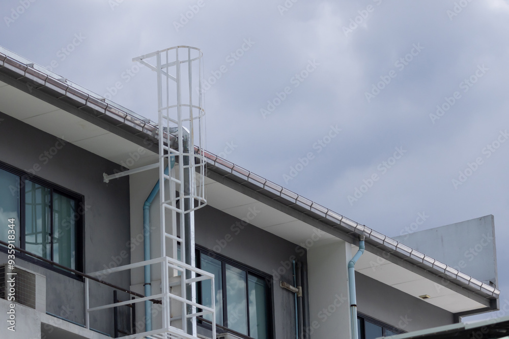 Poster a white ladder on a building with a blue pipe