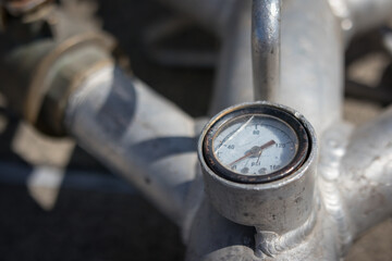 Psi gauge on water pump. Close up of  vintage pressure gauge or measurement dial with broken glass. Used to monitor and control pressure. Selective focus.
