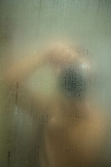 Reflection of man taking picture on steamy bathroom mirror.