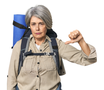 Caucasian mid-age female with hiking gear showing a dislike gesture, thumbs down. Disagreement concept.
