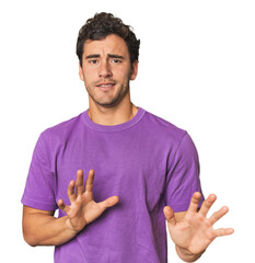 Young Hispanic man in studio rejecting someone showing a gesture of disgust.
