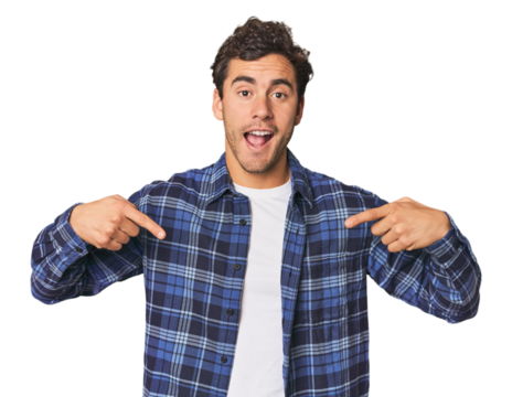 Young Hispanic man in studio surprised pointing with finger, smiling broadly.