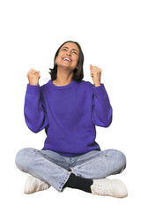 Young Caucasian woman sitting on floor celebrating a victory, passion and enthusiasm, happy...