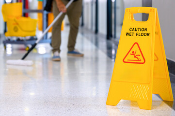 Focus on yellow wet floor warning sign and caution slippery sign background of cleaning using mop mopping the floor cleaning in office with cleaning cart and floor cleaning tools and equipment © เลิศลักษณ์ ทิพชัย
