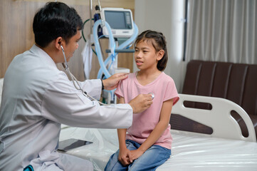Obraz premium Asian doctor in hospital examining and treating child patient using stethoscope to check pulse of sick girl in hospital office. Doctor and nurse health checkup. Pediatrics. Healthcare
