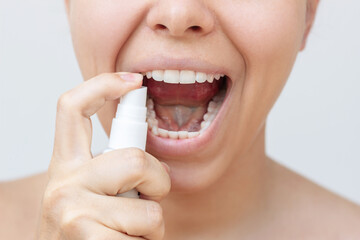 Cropped shot of a young caucasian woman using spray to freshen a breath on a white background....